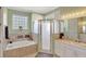 Bright bathroom featuring a bathtub with tile surround, a glass enclosed shower, and a white vanity at 3172 Bayview Ln, St Cloud, FL 34772