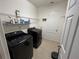 Bright laundry room with a modern washer and dryer, shelving for storage, and neutral-colored walls at 3942 Green Sabal Dr, Orlando, FL 32824