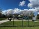 A view of a park with green grass, shade structures, and signage indicating park hours at 4407 Lake Lawne Ave, Orlando, FL 32808