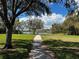 Scenic walking path through a community park with a view of the lake and a shady tree on the right side of the image at 4407 Lake Lawne Ave, Orlando, FL 32808