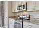 Close-up of the kitchen featuring granite countertops and modern stainless steel appliances and white cabinetry at 5607 Western Sky Pl, St Cloud, FL 34771