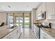 Modern kitchen featuring granite counters, stainless steel appliances, and sliding glass doors to the backyard at 5607 Western Sky Pl, St Cloud, FL 34771