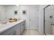 Well-lit bathroom featuring double sinks, grey cabinetry, and a glass shower at 7388 Capstone Dr, Groveland, FL 34736