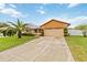 Charming front exterior with two-car garage, stone accents, manicured lawn, and mature palm tree at 8128 Hook Cir, Orlando, FL 32836