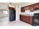 Kitchen with cherry wood cabinets, tile floors, and black appliances at 97 Lake Villa Way, Kissimmee, FL 34743