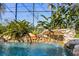 This serene in-ground pool features a rock waterfall with lush, tropical plants, and glass enclosure at 1320 Myrtle Dr, Longwood, FL 32750