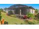 Home's backyard shows the screened patio, manicured lawn, and lush landscaping, creating a private oasis at 1392 Zeek Ridge St, Clermont, FL 34715