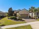 Charming single-story home featuring a well-manicured lawn, paver driveway, and tropical landscaping at 1392 Zeek Ridge St, Clermont, FL 34715
