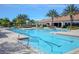 Community pool area with clear blue water, lounge chairs, palm trees, and covered seating with tiled roofing at 1392 Zeek Ridge St, Clermont, FL 34715