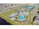 Aerial view of community pool area with tennis and basketball courts, playground, lake, palm trees and neighborhood houses at 14146 Lanikai Beach Dr, Orlando, FL 32827