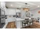 Bright kitchen features white cabinets, stainless steel appliances, wood-look floors, and an island with barstool seating at 14146 Lanikai Beach Dr, Orlando, FL 32827