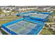Community tennis courts featuring blue fencing, green grass and palm trees with houses in the background at 14146 Lanikai Beach Dr, Orlando, FL 32827