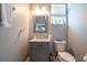 Charming powder room featuring a grey vanity with a marble countertop and decorative window at 14415 Estrella Dr, Orlando, FL 32837