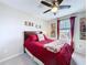 Bedroom with a ceiling fan, a window with curtains, and an inviting red bed with a soft blanket at 16133 Pebble Bluff Loop, Winter Garden, FL 34787