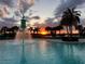 Community pool at sunset featuring palm trees, lounge chairs and a unique fountain at 16133 Pebble Bluff Loop, Winter Garden, FL 34787