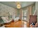 Stylish Bedroom with patterned wallpaper, a cozy rocking chair, and a white crib with decor at 1721 Cheyenne Trl, Maitland, FL 32751