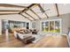 Open-concept living room features exposed wood beams, hardwood floors, and sliding glass doors overlooking the lake at 2118 Lake Dr, Winter Park, FL 32789