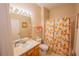 Bright bathroom features a well-lit mirror and a toilet with an orange-themed shower curtain at 2412 Caravelle Cir, Kissimmee, FL 34746