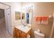 Bathroom features a large well-lit mirror, toilet, and storage under the sink at 2412 Caravelle Cir, Kissimmee, FL 34746