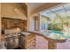 Elegant outdoor kitchen with stainless grill, granite counters, and a view of the refreshing pool at 2442 Heritage Green Ave, Davenport, FL 33837