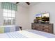 Bedroom featuring two twin beds, ceiling fan, a window, and entertainment center with a large tv at 3185 Pequod Pl, Kissimmee, FL 34746