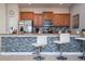 Modern kitchen featuring stainless steel appliances, granite countertops, and stylish breakfast bar with tile accents at 3185 Pequod Pl, Kissimmee, FL 34746