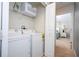 Bright laundry area with washer, dryer, shelving, and view of a bedroom with neutral carpet at 3185 Pequod Pl, Kissimmee, FL 34746
