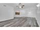 Open-concept living room featuring gray wood floors, ceiling fan and view into the kitchen at 3301 Whitestone Cir # 204, Kissimmee, FL 34741