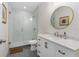 Modern bathroom with a glass-enclosed shower, stylish vanity, and decorative round mirror at 350 E 2Nd Ave, New Smyrna Beach, FL 32169
