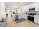 Open-concept kitchen with white cabinets, stainless steel appliances, and wood flooring at 350 E 2Nd Ave, New Smyrna Beach, FL 32169