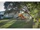 Community playground with colorful slides and play equipment shaded by a large mature tree at 3557 Brighton Park Cir, Orlando, FL 32812