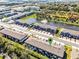 An aerial view of townhomes and apartments showcasing lush landscaping, a pond, and ample parking at 385 Cape Honeysuckle Pl, Sanford, FL 32771