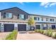 Inviting townhome exterior features a brick driveway, dark gray garage doors, and a delightful porch swing at 385 Cape Honeysuckle Pl, Sanford, FL 32771