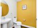 Bright half bathroom with a large circular mirror, pedestal sink, and vibrant yellow walls at 5433 Keaton Springs Dr, Lakeland, FL 33811