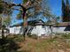 View of the home's backyard with side exterior, mature trees, and partially fenced yard at 592 N 8Th St, Eagle Lake, FL 33839