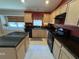 Eat-in kitchen featuring black appliances, granite countertops, maple cabinets, and tile floors at 619 Blenheim Loop, Winter Springs, FL 32708