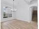 Bright dining room with a large window, modern chandelier, and light wood-look flooring at 674 Whisper Woods Dr, Lakeland, FL 33813