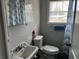 Bathroom with a white sink, toilet, blue tile, a window and a decorative blue curtain at 914 2Nd St, Orlando, FL 32824