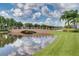 Scenic bridge over a tranquil lake reflects the surrounding lush greenery and cloudy sky, creating a serene view at 11846 Nautica Dr, Orlando, FL 32827