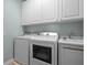 A well-lit laundry room with modern washer, dryer, and utility sink at 11846 Nautica Dr, Orlando, FL 32827