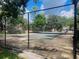 View of a community tennis court surrounded by trees and secured with a chain-link fence at 136 Raintree Dr, Longwood, FL 32779