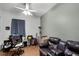 A bedroom featuring a brown leather couch, desk, workstation, guitar, ceiling fan and wood flooring at 1562 Auburn Oaks Ct, Auburndale, FL 33823