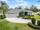 Well-manicured home featuring a spacious driveway, lush landscaping, and a two-car garage at 1562 Auburn Oaks Ct, Auburndale, FL 33823