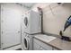 Bright laundry room featuring stacked washer and dryer, sink with countertop, and storage shelves at 1562 Auburn Oaks Ct, Auburndale, FL 33823