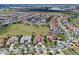 Wide aerial view of a neighborhood featuring homes with red tile roofs next to a large green field at 15644 Panther Lake Dr, Winter Garden, FL 34787