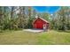 Quaint red outbuilding featuring a concrete patio surrounded by a verdant lawn and mature trees at 16318 Hamilton Dr, Orlando, FL 32833