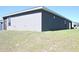 A view of the spacious backyard with a gray stucco exterior and sunny sky at 2294 Sunset Way, Davenport, FL 33837