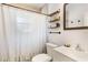 This bathroom features a shower with curtain, tile accents, and floating wood shelves at 2303 Mahoney Ave, Leesburg, FL 34748