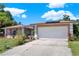 Inviting exterior showcasing a two-car garage, well-maintained lawn, and attractive landscaping at 30 Cornwall Ct, Casselberry, FL 32707