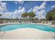 Large community pool surrounded by sun loungers and mature palm trees under a blue sky at 3162 Sun Lake Ct # B, Kissimmee, FL 34747